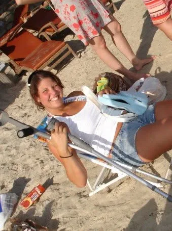 Pamela laughing in a beach chair with her leg in a cast on a sandy beach in Mallorca
