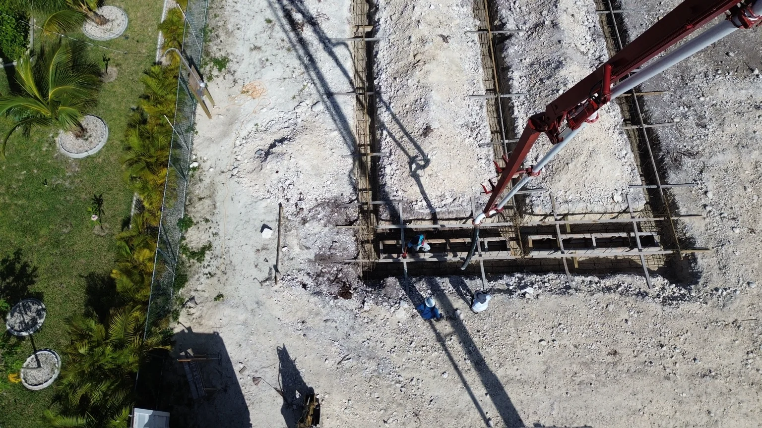 Overhead drone view of foundation work and a concrete pump at a Grand Bahama construction site