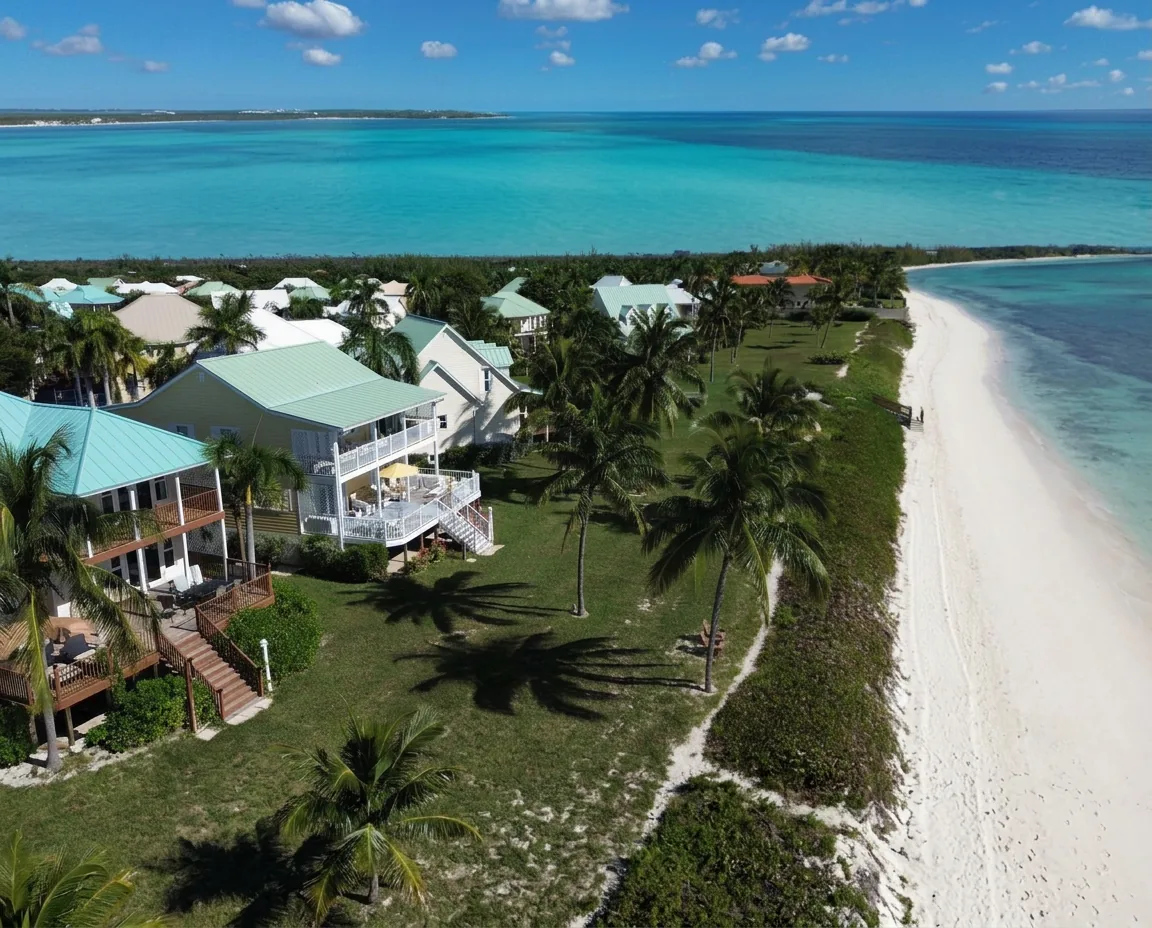 Aerial of waterfront homes among palms beside the beach and turquoise water in Grand Bahama
